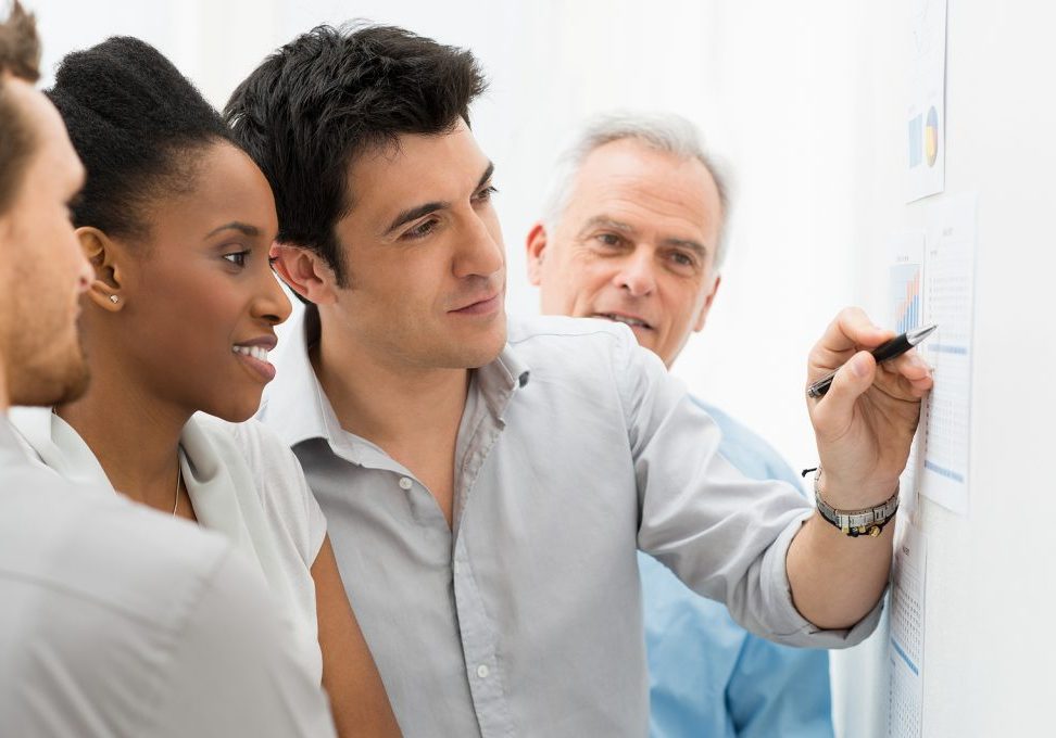 Group Of Business People Analyzing Graphs and Charts in Office