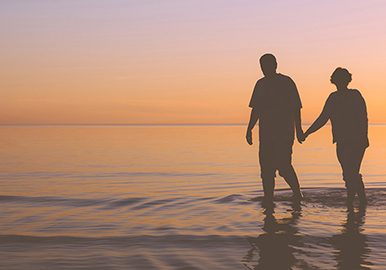 Senior couple walking holding hands at sunset